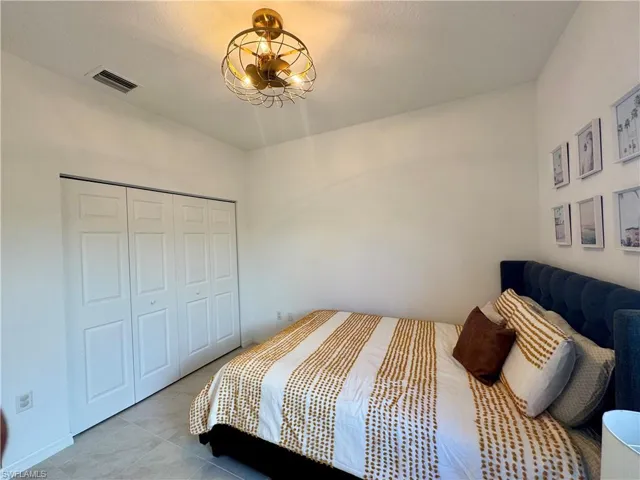 Bedroom featuring a closet, visible vents, an inviting chandelier, and light tile patterned floors