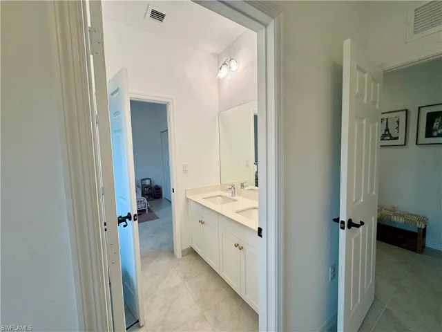 Ensuite bathroom featuring a sink, double vanity, connected bathroom, and visible vents