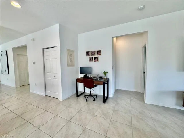 Home office featuring light tile patterned floors, baseboards, and a textured ceiling