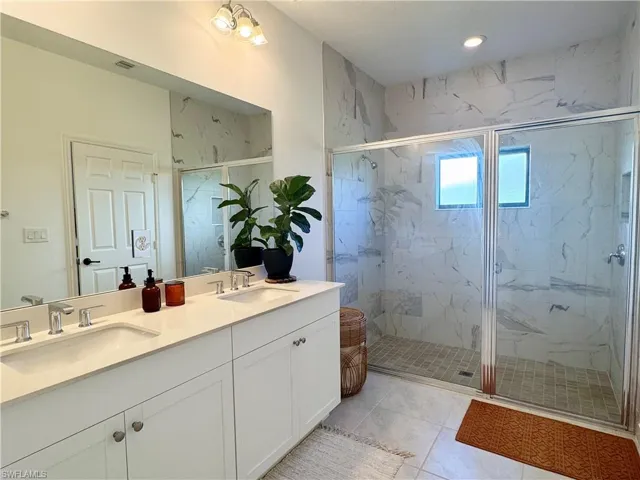Bathroom featuring double vanity, a sink, a marble finish shower, and recessed lighting