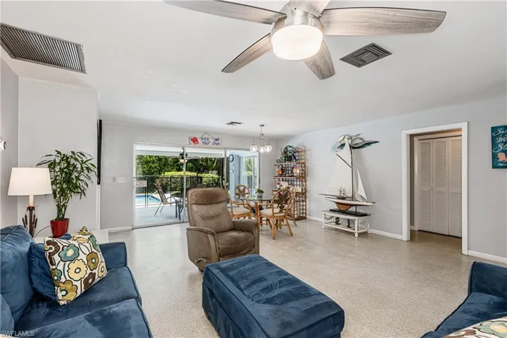 Living room featuring speckled floor, ceiling fan, and a chandelier