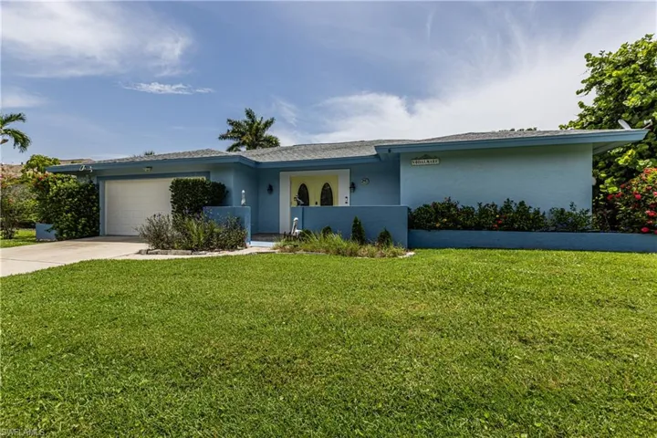 View of front facade with a garage, driveway, stucco siding, and a front lawn