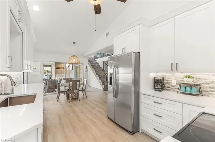 Kitchen with tasteful backsplash, stainless steel fridge with ice dispenser, white cabinets, and lofted ceiling