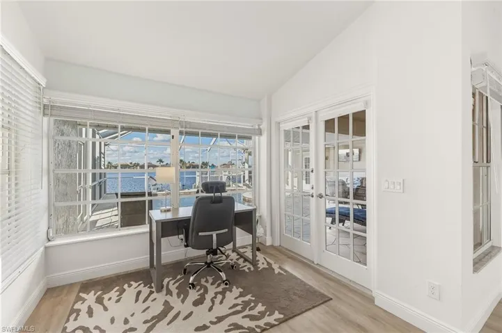 Home office with vaulted ceiling, light wood-type flooring, french doors, a water view, and a sunroom