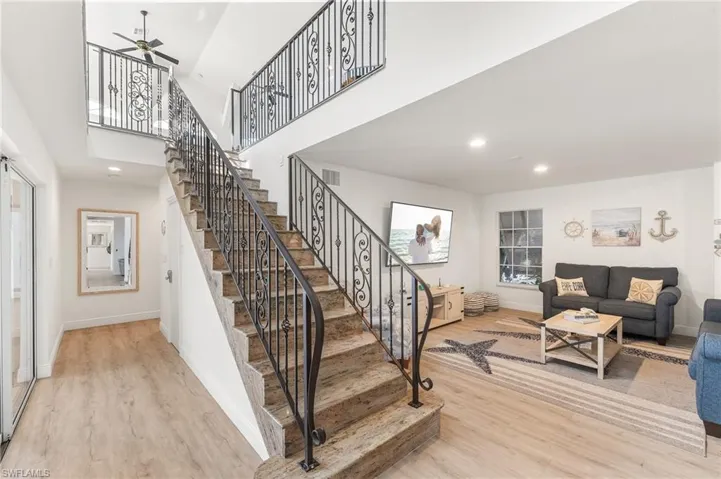 Staircase with wood finished floors, a towering ceiling, recessed lighting, and a ceiling fan
