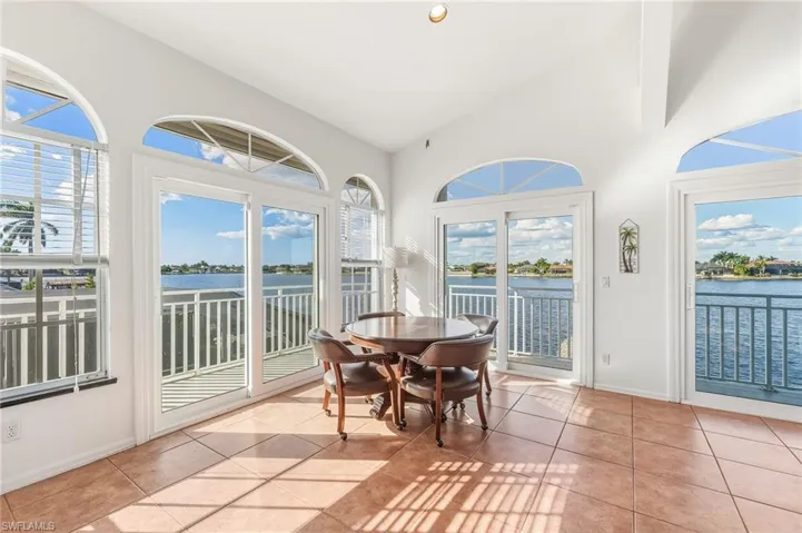 Sunroom / solarium with tile patterned floors, a water view, recessed lighting, and high vaulted ceiling