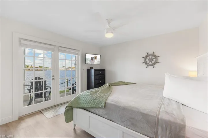 Bedroom featuring access to outside, french doors, wood finished floors, and a ceiling fan