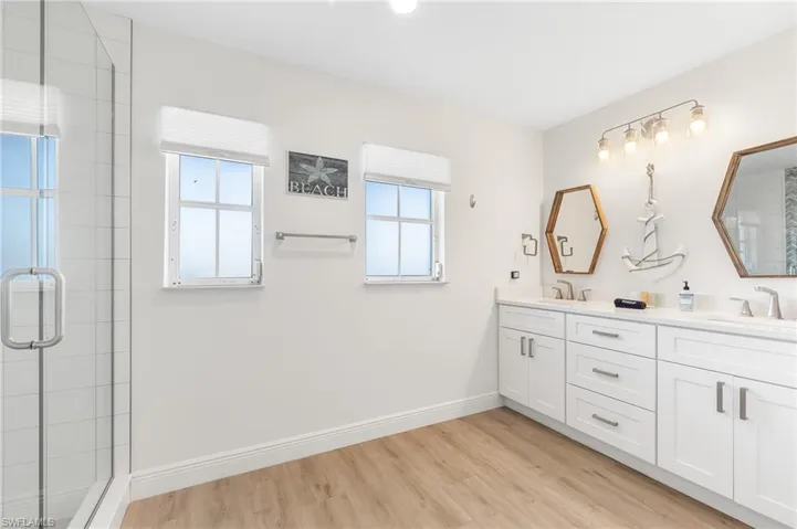 Full bathroom with a stall shower, double vanity, and light wood-style floors