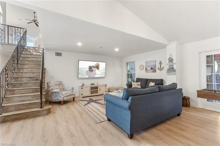 Living room featuring light wood-type flooring, recessed lighting, stairway, and high vaulted ceiling