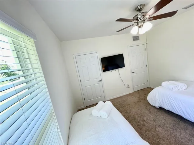 Carpeted bedroom with a ceiling fan and baseboards