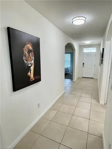 Entryway featuring light tile patterned floors, arched walkways, and baseboards