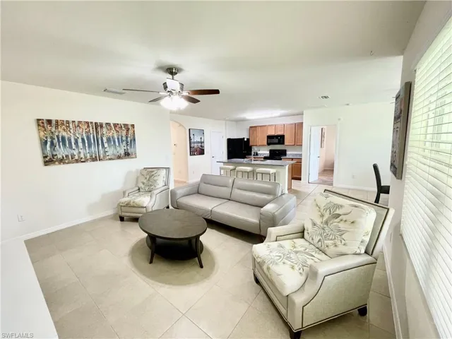Living area with baseboards, ceiling fan, and arched walkways