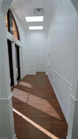 Hallway with dark wood finished floors and a drop ceiling