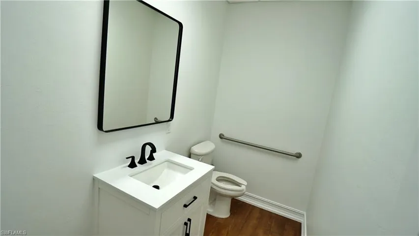 Half bath with vanity and dark wood-style flooring