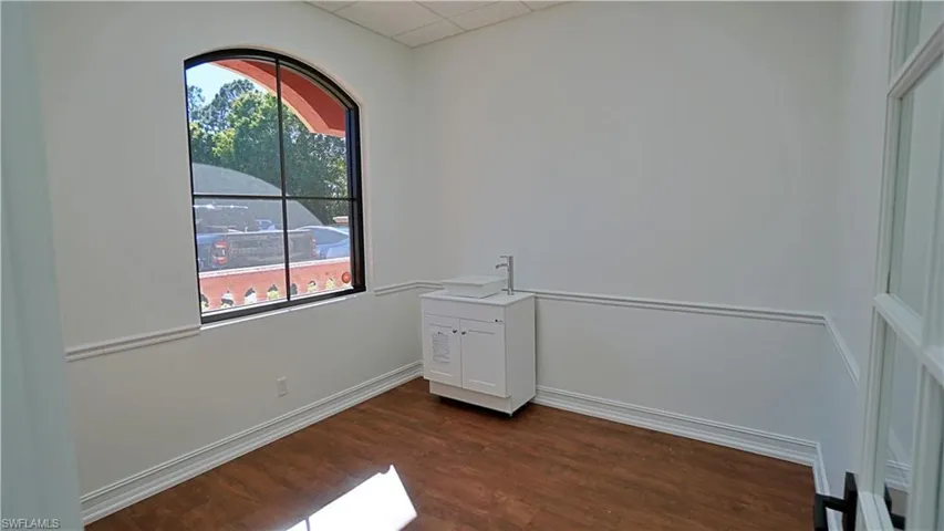 Empty room featuring dark wood-style flooring and a drop ceiling