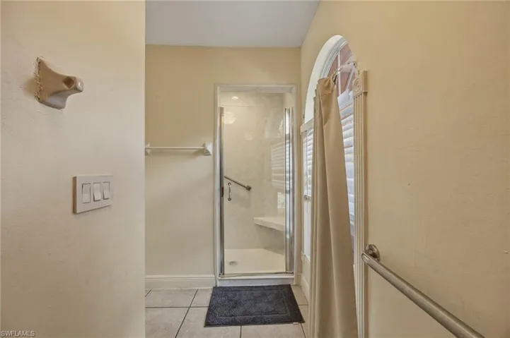 Bathroom featuring a shower stall and light tile patterned flooring
