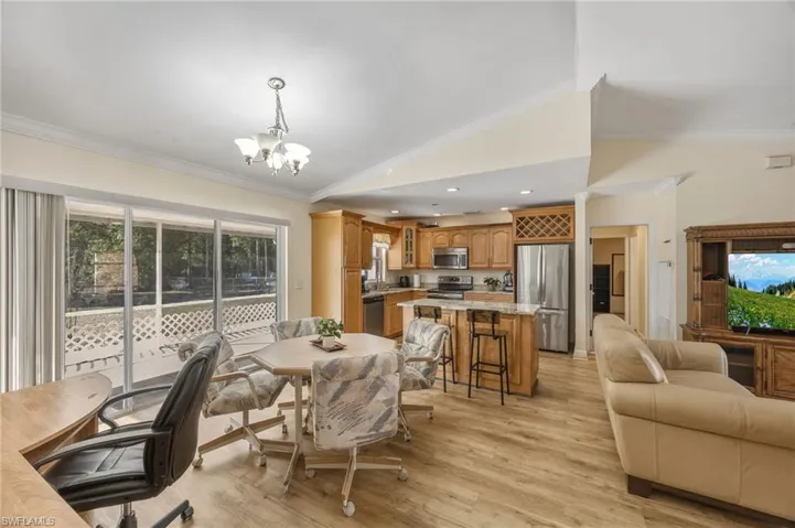 Dining area with lofted ceiling, crown molding, light wood-style flooring, suspended lighting, and healthy amount of natural light