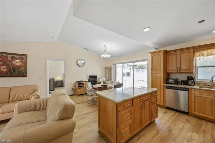 Kitchen featuring open floor plan, light stone countertops, dishwasher, light wood-type flooring, and ornamental molding