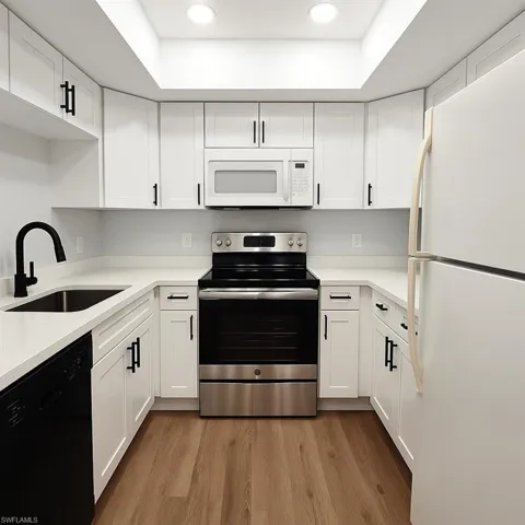 Kitchen featuring white appliances, a sink, white cabinets, and recessed lighting