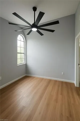 Spare room with ceiling fan, light wood-type flooring, and baseboards