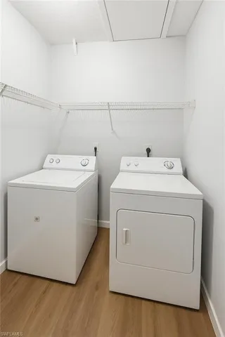 Laundry area with washing machine and clothes dryer, light wood-style flooring, and baseboards