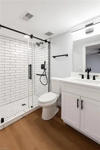 Full bathroom with vanity, a shower stall, wood finished floors, and toilet