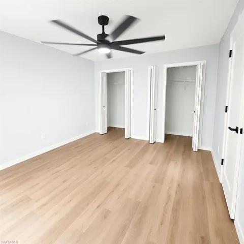 Unfurnished bedroom featuring two closets, light wood finished floors, baseboards, and ceiling fan