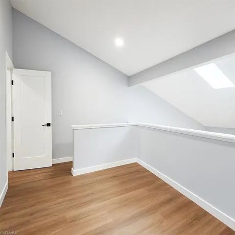 Additional living space featuring lofted ceiling, baseboards, light wood-style flooring, and recessed lighting