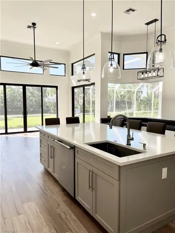 Kitchen featuring dishwasher, sink, a kitchen island with sink, and decorative light fixtures
