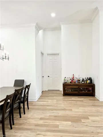 Open bar/Dining room featuring light wood-type flooring, crown molding, and a chandelier