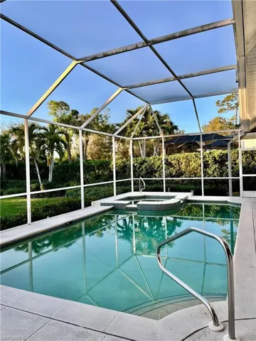 View of pool with screen enclosure and hot tub