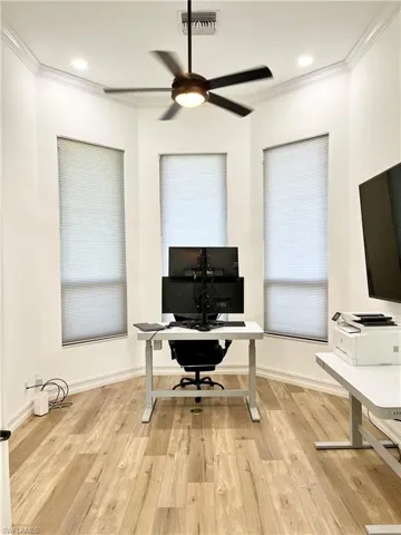 Office area with light hardwood / wood-style flooring, ceiling fan, and ornamental molding