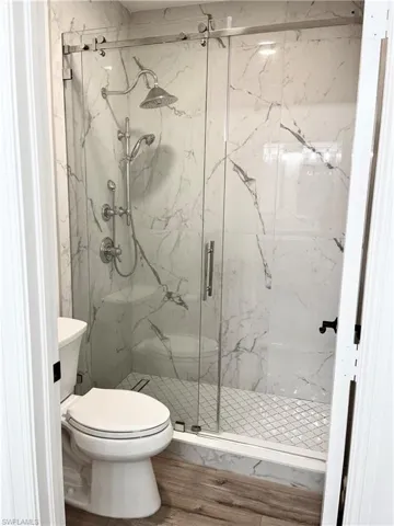 Bathroom 2 with hardwood / wood-style flooring, toilet, and an enclosed shower