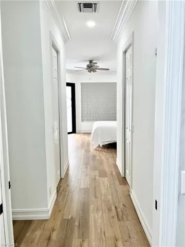 Master Corridor with light hardwood / wood-style floors and ornamental molding