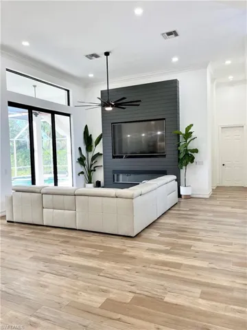 Open Living room with ceiling fan, light hardwood / wood-style flooring, and ornamental molding