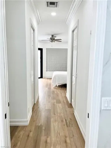 Corridor master bedroom to master bathroom and walk in closets with light hardwood / wood-style floors and ornamental molding