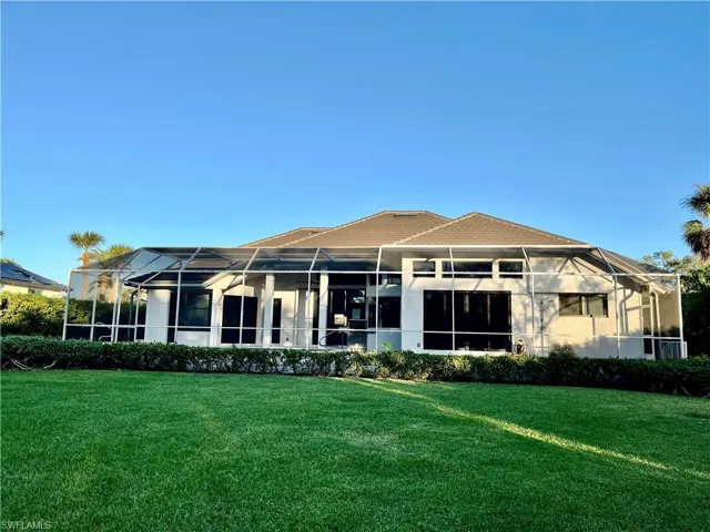 Rear view of house with a lawn and screen enclosure