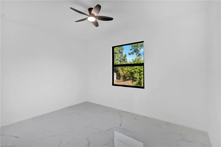Spare room featuring marble look tiles and a ceiling fan