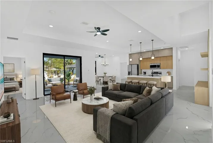 Living room featuring a ceiling fan, a raised ceiling, and a chandelier