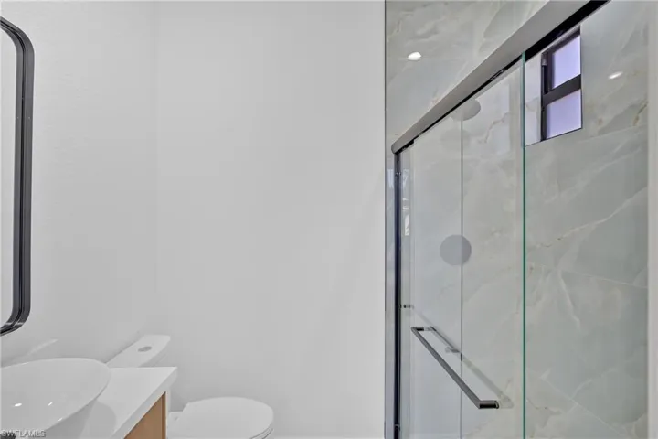 Full bathroom featuring a marble finish shower and vanity