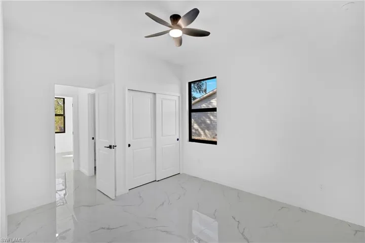 Unfurnished bedroom with light marble finish flooring, a closet, and ceiling fan