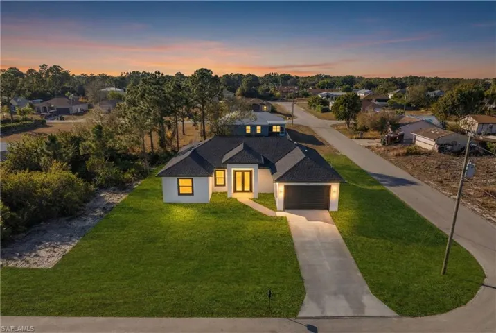 View of front facade with a front lawn, driveway, a residential view, roof with shingles, and a garage