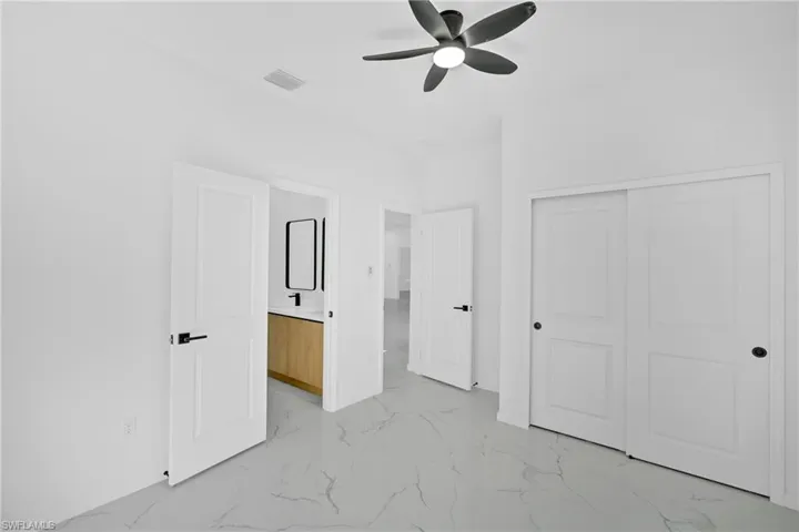 Unfurnished bedroom featuring light marble finish floors, ceiling fan, and a closet