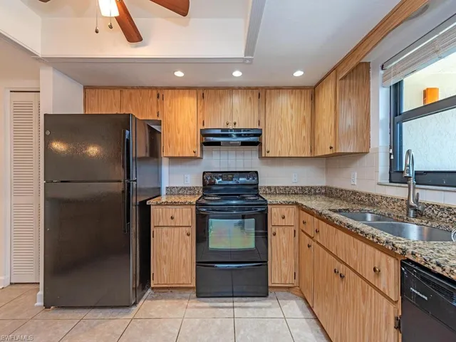 Kitchen with black appliances, dark stone countertops, decorative backsplash, recessed lighting, and light tile patterned floors