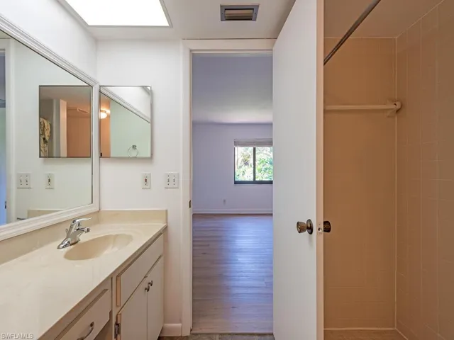 Full bathroom featuring a tile shower, vanity, and light wood-style flooring
