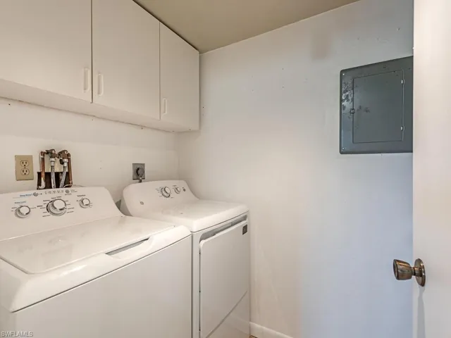 Laundry room with electric panel, cabinet space, and washing machine and clothes dryer
