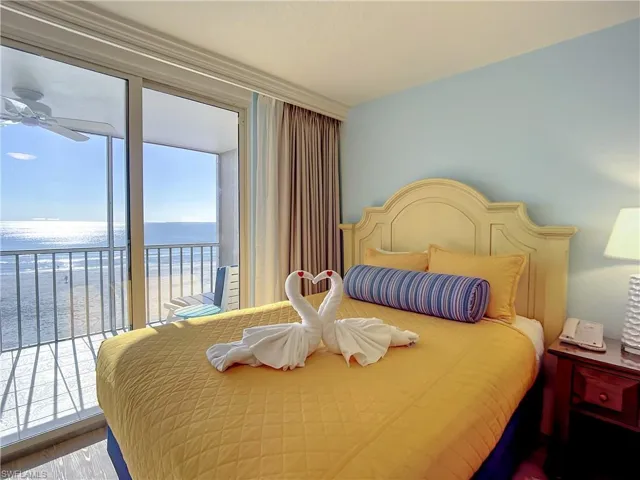 Bedroom featuring wood-type flooring, ceiling fan, a water view, a view of the beach, and access to outside