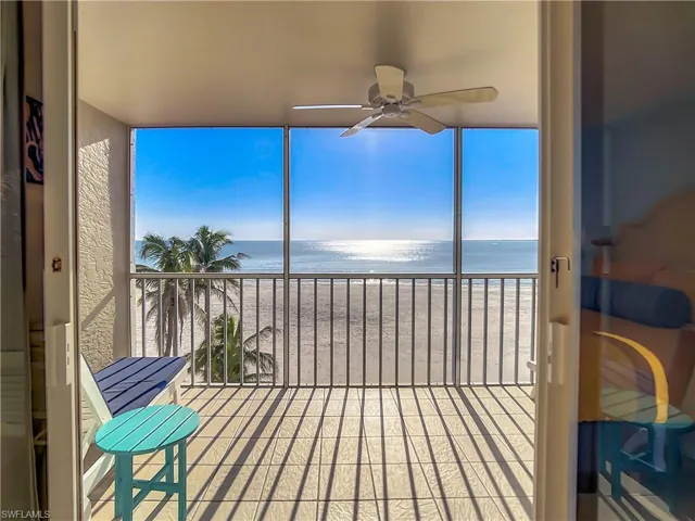 Sunroom featuring a view of the beach, a water view, and ceiling fan
