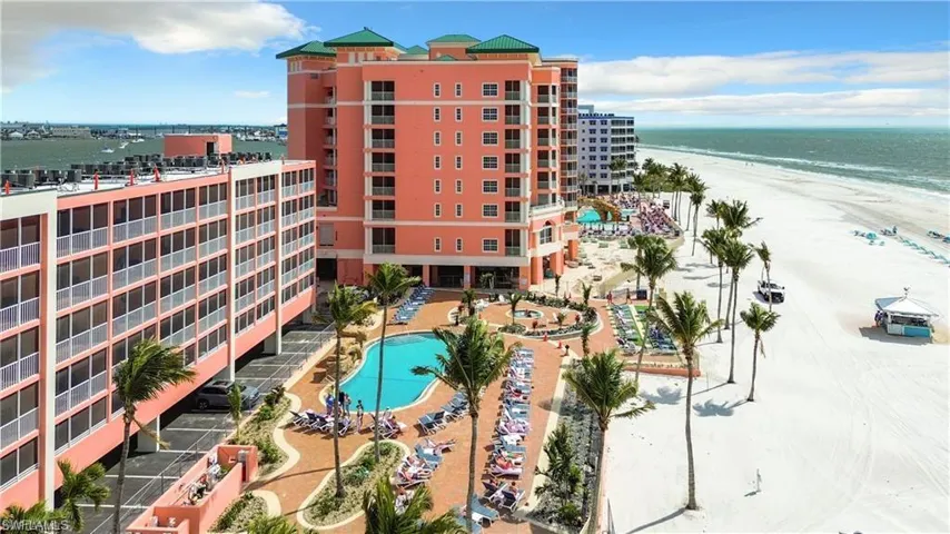 View of building exterior featuring a view of the beach, a water view, and a community pool