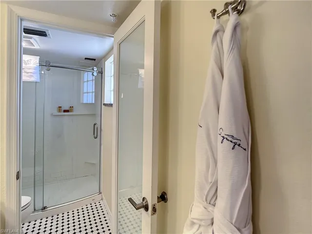 Bathroom featuring a shower with door, tile patterned flooring, and toilet
